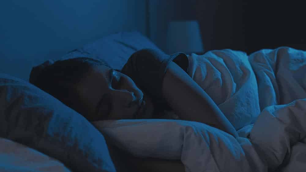 Woman in bed in a dark room to illustrate cannabis for sleep.